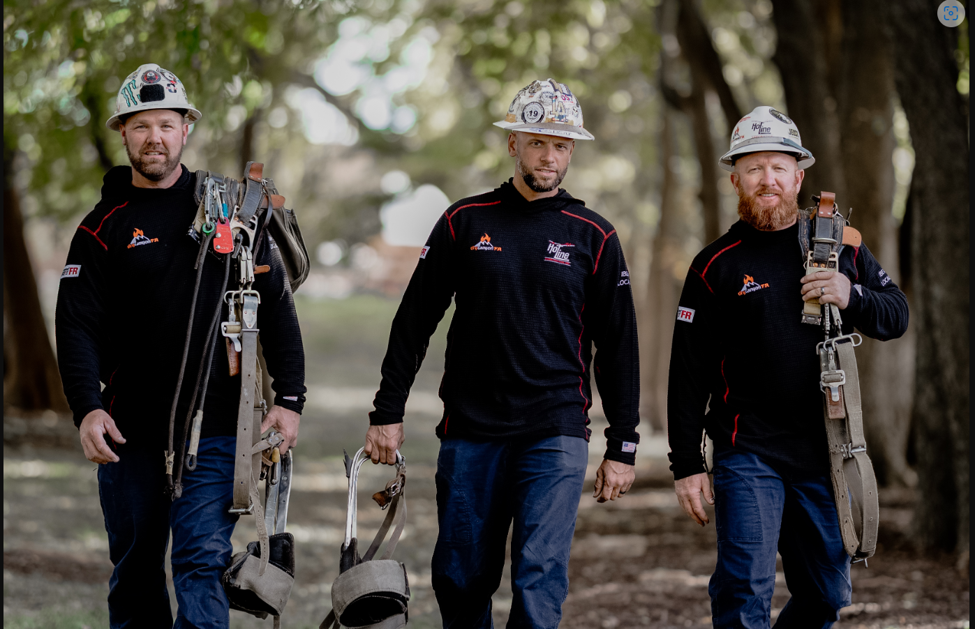 Three construction workers walking with safety gear outdoors.