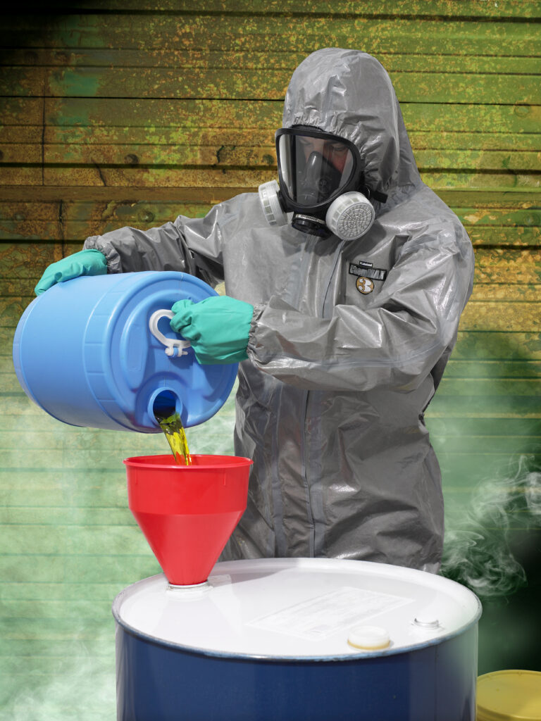 Ein Arbeiter in ChemMax -Chemikalienschutzkleidung füllt eine dampfförmige Chemikalie in ein Fass.