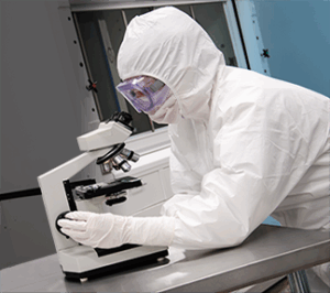 Scientist in lab gear using microscope