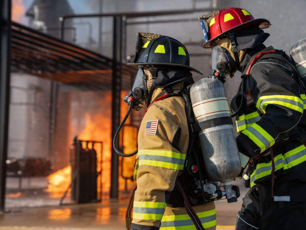 Firefighters fighting industrial fire with equipment