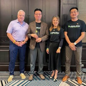Four people standing together, one holding an award.