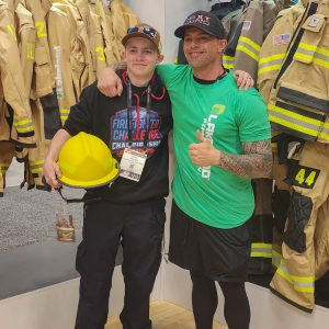 Two men smiling at firefighter gear expo.